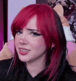 a woman with red hair and freckles is making a funny face while sitting in front of a stuffed animal .