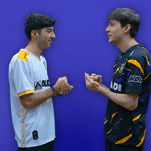 two men standing next to each other with one wearing a adi shirt