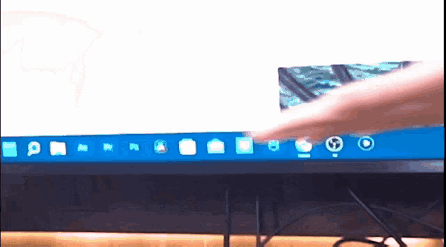 a person 's hand is pointing at a computer screen with a bunch of icons on it