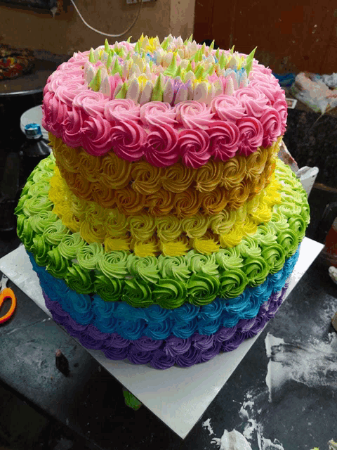 a rainbow colored cake with flowers on top