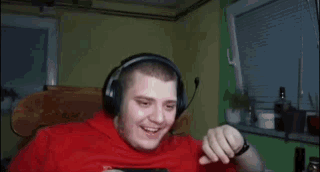 a man wearing headphones and a red shirt is dancing in front of a window .