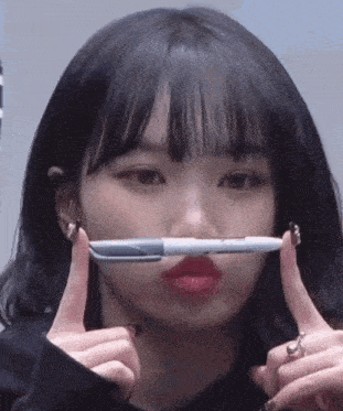 a young woman is holding a pen in her mouth .