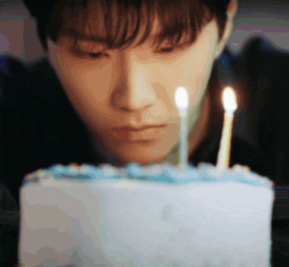 a close up of a person looking at a birthday cake