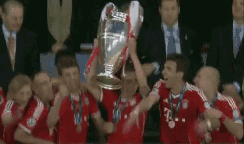 a group of soccer players are holding a trophy in the air .