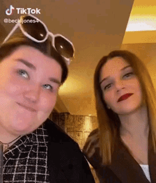 two women are posing for a picture and one has sunglasses on her head