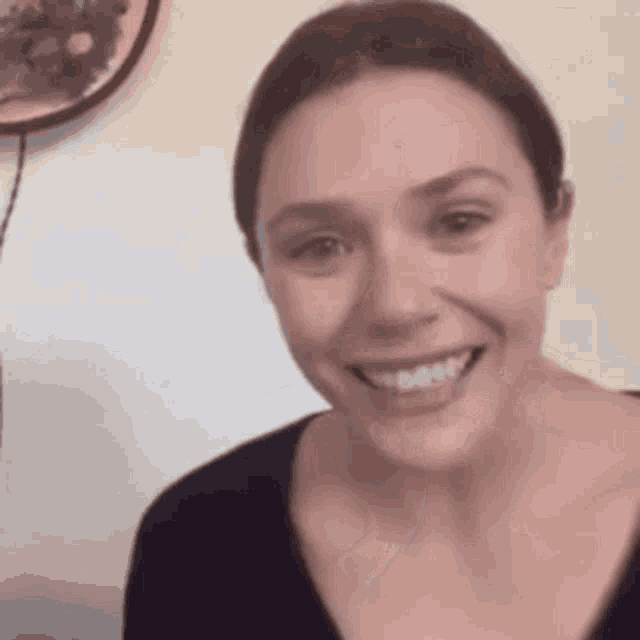 a close up of a woman 's face smiling and looking at the camera .