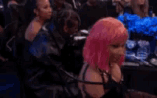 a woman with pink hair is sitting in a crowd at a party .
