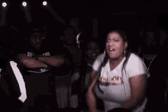 a woman in a white t-shirt is screaming in a crowd .
