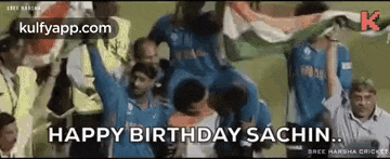 a group of cricket players are holding up their arms in the air in front of a crowd of people .