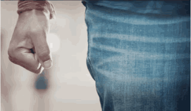 a close up of a person 's fist against their blue jeans