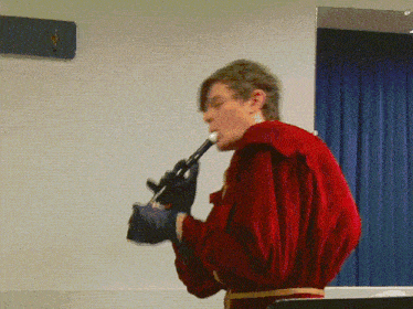 a man in a red jacket is playing a recorder