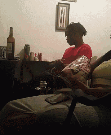 a man in a red shirt sits in a chair holding a bag of doritos chips