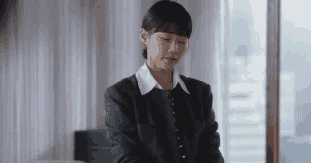 a woman in a black jacket and white collared shirt