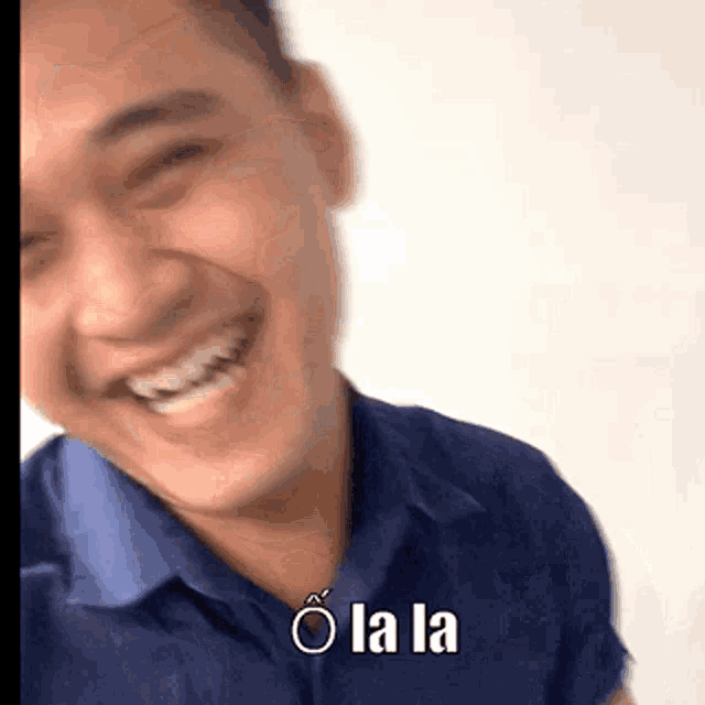 a man in a blue shirt is smiling with the words o la la written below him
