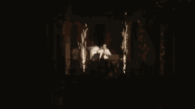 a man and woman are dancing on a balcony at night with fireworks behind them .