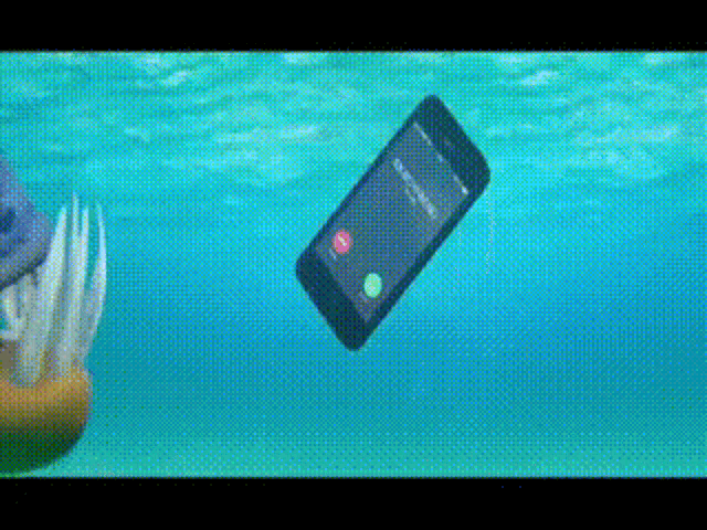 a cell phone is floating in the water with a toothbrush in the background