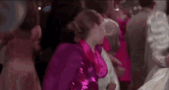 a woman in a pink dress is dancing in a room with a bun .
