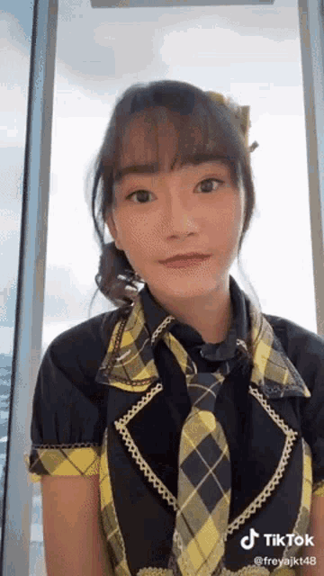 a girl wearing a yellow and black plaid shirt and tie .