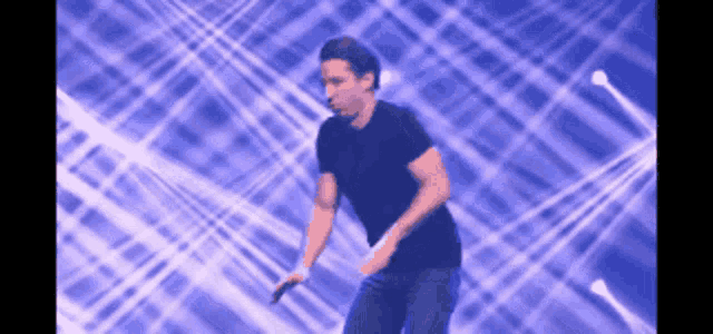 a man in a black shirt is holding a microphone and dancing on a stage