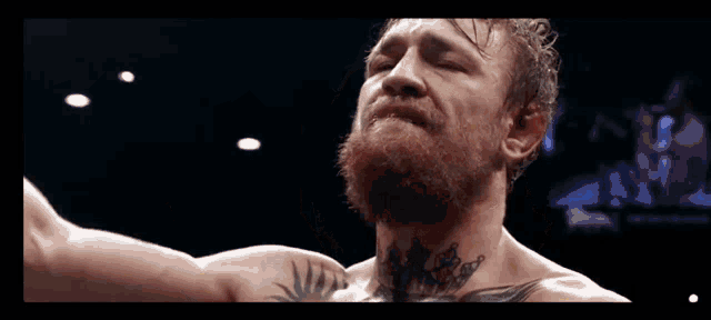 a man with a beard and a tattoo on his neck holds his arm up