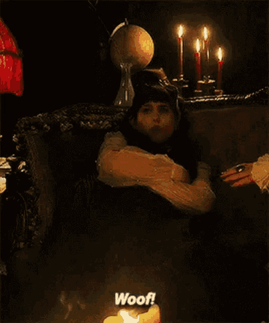 a woman is sitting in a chair next to a lit candle and says woof