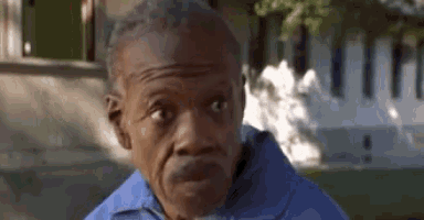 a man in a blue shirt is making a funny face while standing in front of a building .