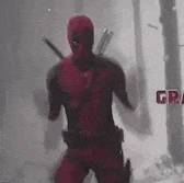 a man in a deadpool costume is standing in a forest holding a sword .