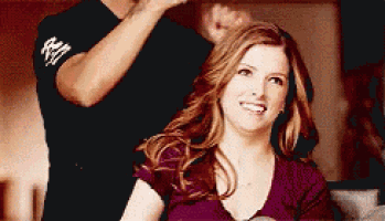 a man is brushing a woman 's hair while she smiles .