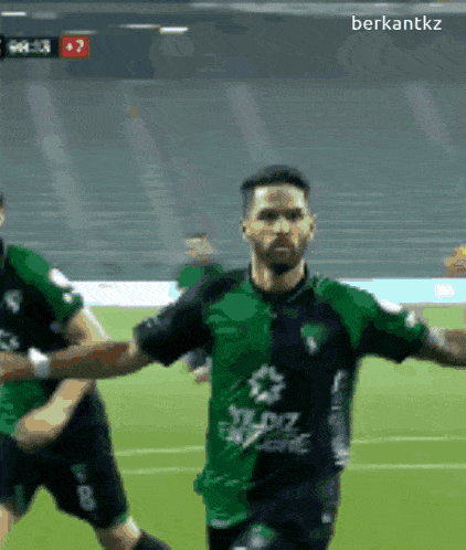 a soccer player wearing a green and black shirt with a star on the front celebrates a goal