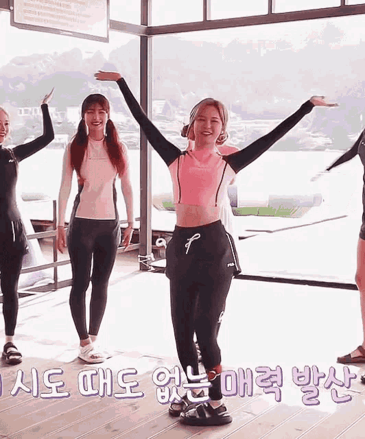 a group of women are standing next to each other with their arms outstretched in front of a window .