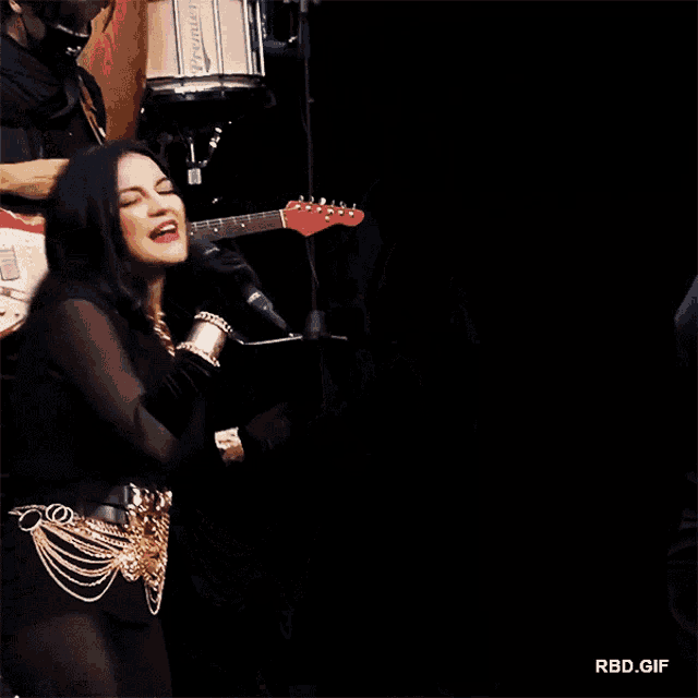 a man playing a guitar next to a woman singing into a microphone with rbd.gif at the bottom