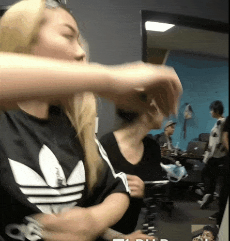 a woman wearing a black and white adidas shirt holds her hand up
