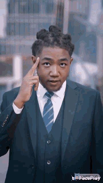 a man in a suit and tie is pointing his finger at his forehead .