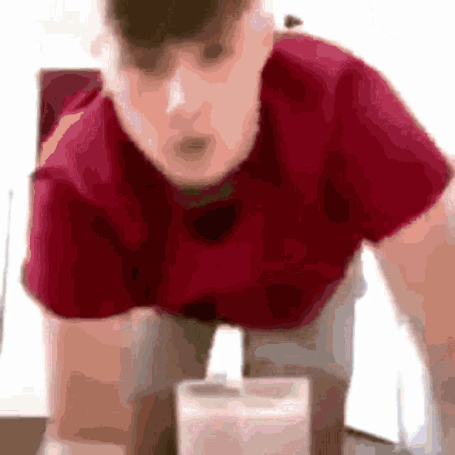 a blurry picture of a man in a red shirt looking at something