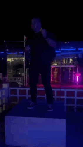 a man in a black shirt is standing on a podium in front of a neon sign that says casino