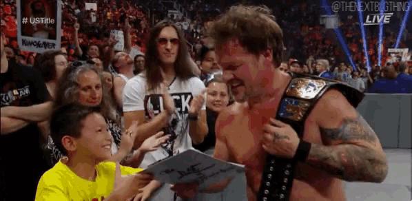 a man with a championship belt is signing a piece of paper for a young boy .