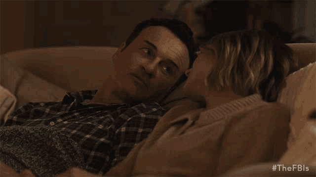 a man and woman laying on a couch with the fbi written on the bottom right