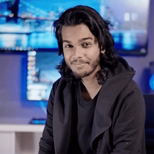 a young man with long hair and a beard is smiling