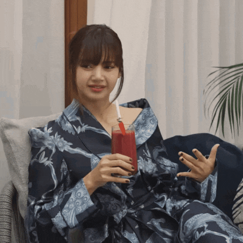 a woman in a blue robe is holding a glass of red liquid