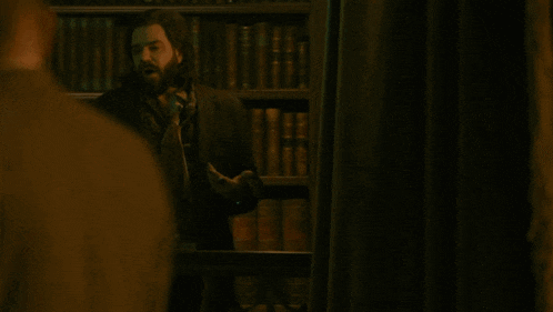 a man standing in front of a bookshelf with the words you wank yours written below him