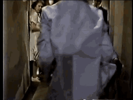 a man in a white coat is walking down a hallway with a group of people behind him .