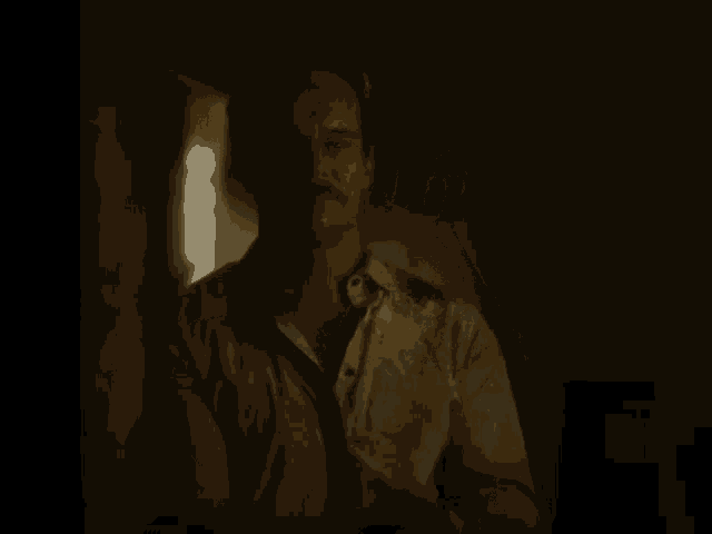 a man in a shirt and tie is sitting in a dark room looking at the camera .