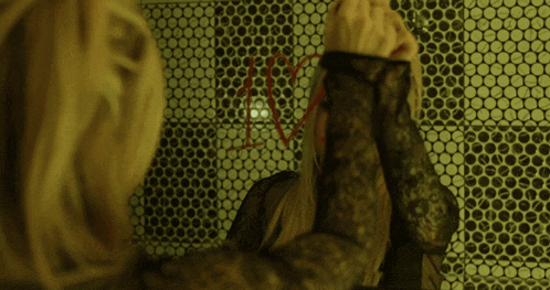 a woman is looking at herself in a mirror and has a red string in her hair