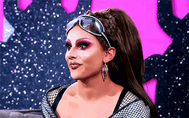 a drag queen wearing sunglasses and a headband with rhinestones on it