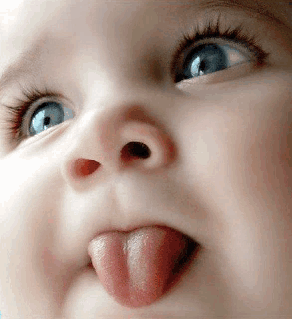 a close up of a baby 's face with its tongue sticking out