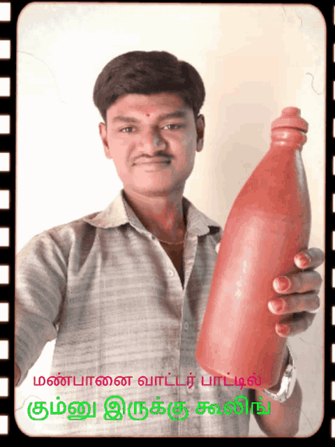 a man is holding a red bottle in his hand with a foreign language written on the bottom