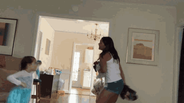 a woman in a white tank top and shorts is holding a child