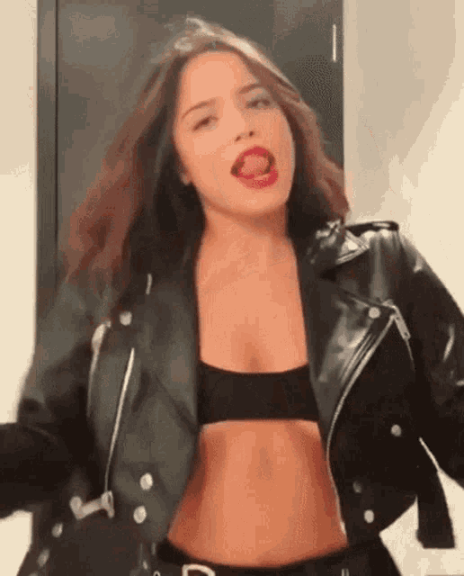 a woman wearing a black leather jacket and a black bra is dancing .