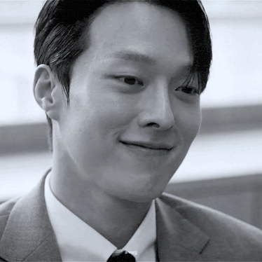 a close up of a man in a suit and tie smiling in a black and white photo .