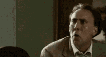 a man in a suit and tie is making a funny face while sitting at a table .